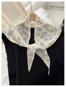 Detail of floral triangular scarf in white and yellow tied on a black shirt neckline