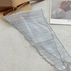 Detail showing the light grey pleated linen fabric with wavy lettuce edge and wash label