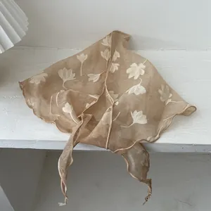 Detail van bloemige zijden driehoekige sjaal met magnoliaprint en golvende randen