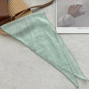 Detail of light green lace triangle scarf with floral embroidery on grey carpet background