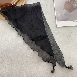 Detail of black translucent scarf featuring wavy edges and delicate ball pendant charms