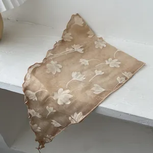 Close-up van een semitransparante bloemensjaal met ruches en witte bloemenpatronen