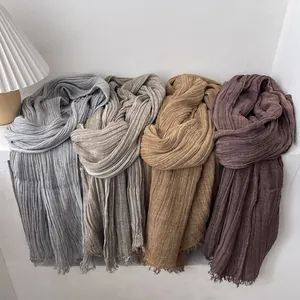 Detailed texture of wrinkled cotton linen scarves in neutral tones with frayed edges
