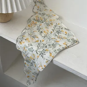 Detail of floral triangular scarf with yellow patterns and grey wavy edge on wood
