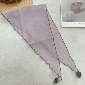 Detailed view of grey-purple lace triangle scarf with decorative mini pompom trim edges
