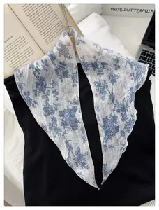 Detail of vintage blue floral embroidery on ivory linen scarf styled on a black top