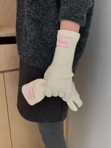 Detail of cream knitted gloves featuring vintage pink fabric label and soft wool texture