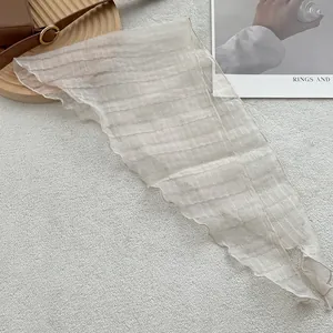Detail of light beige linen triangle scarf with textured grid pattern and care label