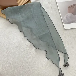Detail of sage green lace scarf with scalloped edges and delicate pompom pendants