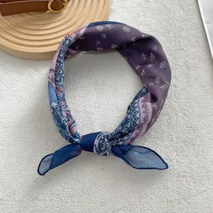 Detail of vintage paisley silk scarf with purple daisy pattern on a white plush background