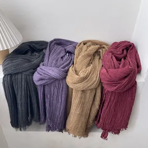 Detailed view of four pleated cotton scarves in grey, purple, camel, and burgundy shades