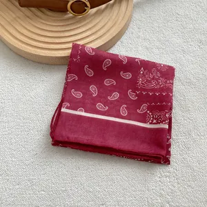 Bandana classica rossa con motivo paisley bianco esposta su un vassoio di legno vintage