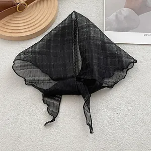 Detail of black semi-transparent linen headscarf with soft pleated texture on white background