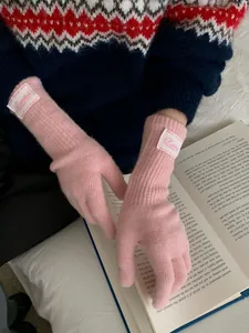 Detail of pink ribbed knit gloves with fabric label on a decorative book background