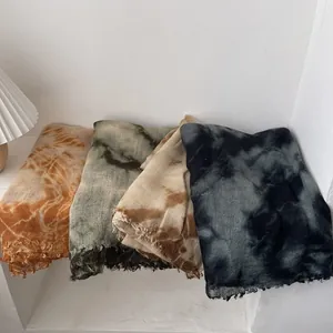 Artistic tie-dye wool scarves in assorted colors with fringed edges on a minimalist desk