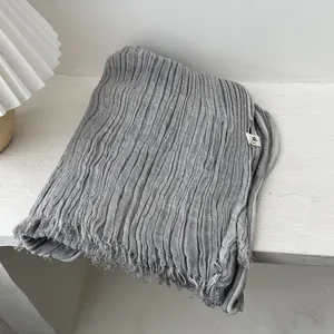 Detail of grey pleated linen cotton scarf featuring raw edges and soft textured fabric