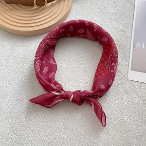 Elegante foulard in seta bordeaux con motivo paisley annodato su supporto in legno rustico