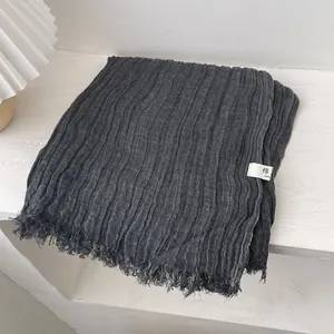 Detail of dark grey pleated cotton scarf with frayed edges and texture close-up