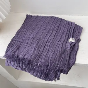 Macro detail of dark purple crinkled cotton scarf featuring raw edges and soft texture
