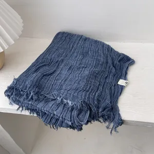 Detail of navy blue pleated cotton scarf featuring raw edges and soft textured fabric