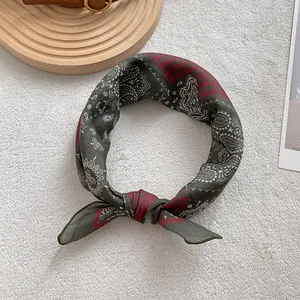 Vista dettagliata di un foulard quadrato con motivo paisley annodato nei toni verde e rosso