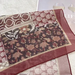 Close-up of retro floral pattern and hemmed edge on a dark red cotton square scarf