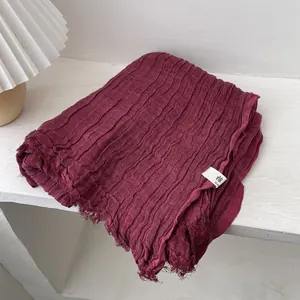 Detail shot of pleated burgundy cotton scarf with natural raw edges on white desk