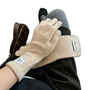 Beige knitted gloves with brand patch showing warm soft texture for winter outdoor wear