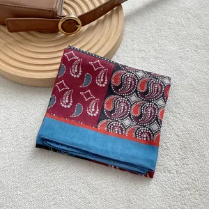 Detail view of a retro paisley print silk scarf on a wooden display tray