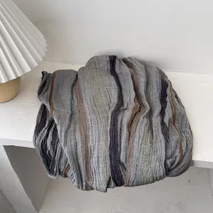 Detailed close-up of textured vertical stripes and pleated fabric on a cotton linen shawl