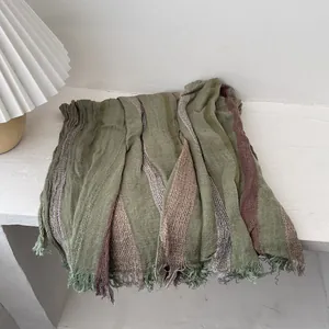 Detail of dark green striped cotton linen scarf featuring natural frayed fringe edges