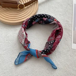 Detail of a vintage paisley print square silk scarf tied on a brown leather handbag strap