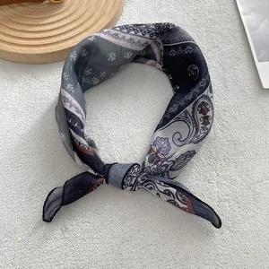 Close-up of vintage paisley cotton linen silk scarf tied in a knot on white surface