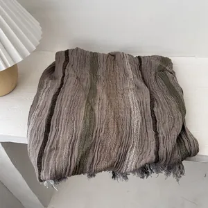 Detailed view of striped linen shawl with crinkle texture and gray fringe tassels
