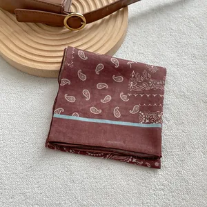 Vista dettagliata del foulard marrone con motivo paisley su vassoio di legno