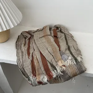 Detail of vintage linen scarf texture with earth-tone stripes and fine fringe edges
