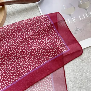 Polka dot red silk scarf with purple trim on white plush background for a stylish look