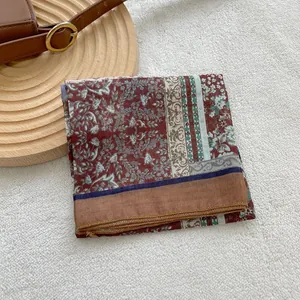 Detailed view of dark red retro floral cotton scarf with geometric borders on wood tray