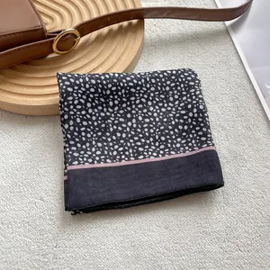 Detailed texture of black and white pebble print silk scarf with pink accent border