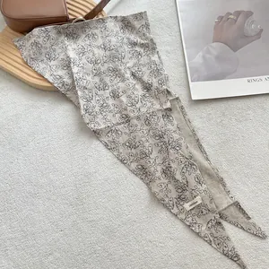 Detail of 100% linen floral triangle scarf on a textured cream rug with elegant props