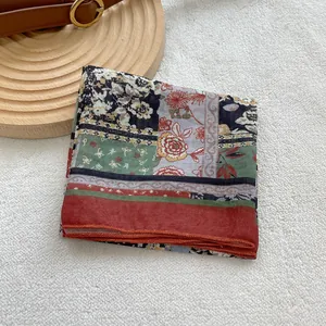 Close-up of retro floral square scarf with rolled edges on a white plush background