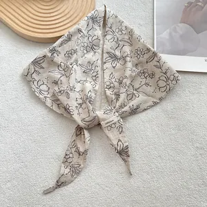 Detail of 100% linen triangle scarf with black hand-drawn floral print on beige fabric