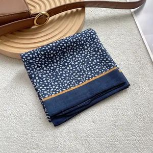 Close-up of a blue leopard pattern silk scarf with orange border on white fur