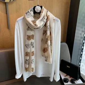 Detail of beige scarf featuring cartoon teddy bear prints with classic plaid patterns