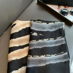 Détail de foulards léopard avec des rayures dorées métallisées sur le tissu soyeux