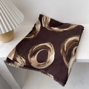 Detail of soft brown scarf with interlocking ring prints and delicate frayed fringe edges