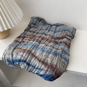 Détail d'une écharpe en lin plissée avec rayures tie-dye et texture froissée riche
