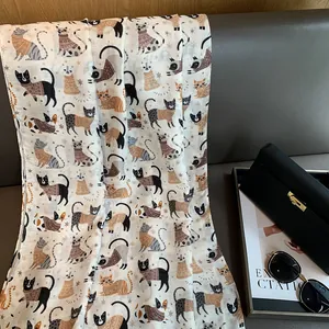 Detailed view of lightweight beige linen scarf featuring colorful cartoon cat illustrations