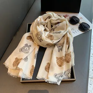 Detailed macro view of teddy bear pattern and fringed edges on a beige cotton scarf