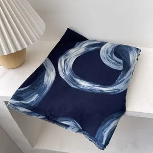 Detail of navy blue scarf featuring artistic hand-drawn interlocking ring patterns and fringe